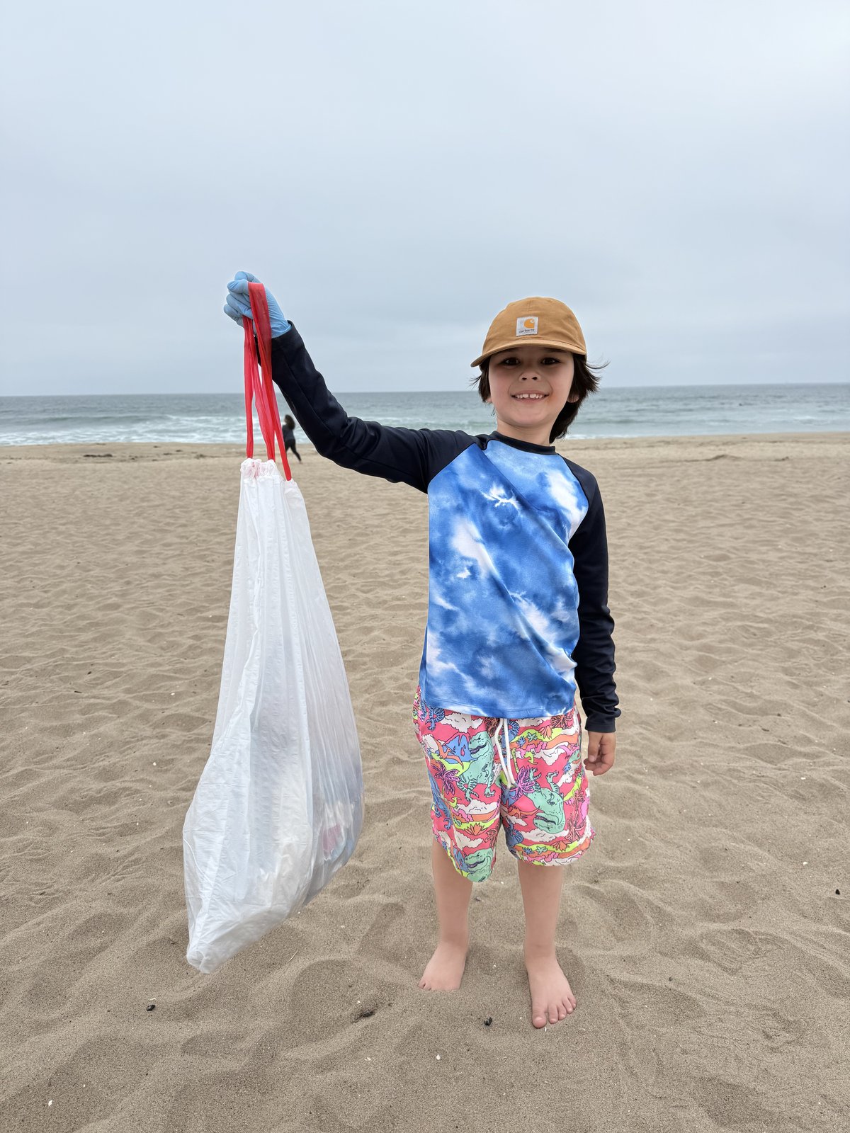 Jefferey holding a bag of collected trash during a beach clean up