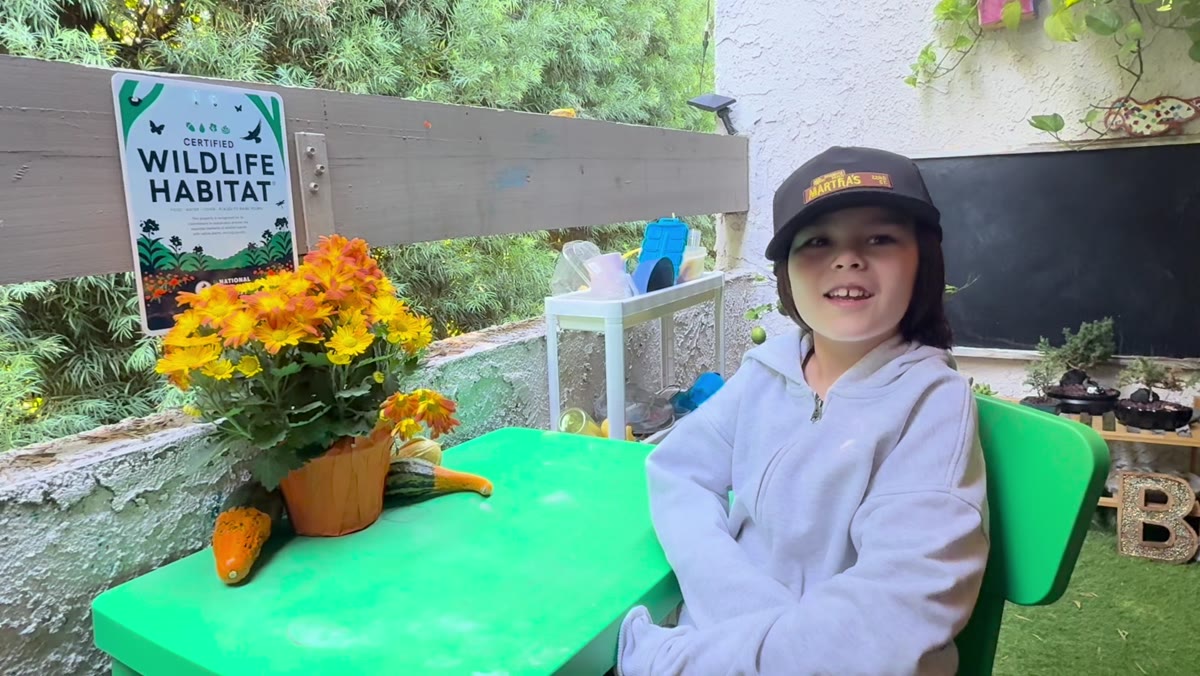 Jefferey sitting beside his Certified Wildlife Habitat sign